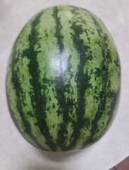 watermelon on white gray wooden table, oval shape whole watermelon