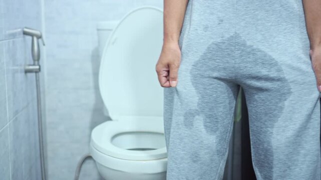 Female have problem with stress urinary incontinence, unable to control urine flow, standing in the bathroom with wet pants caused by sudden bladder leaks