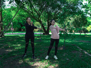 Asian woman in sportswear stretching and warming up before morning jogging. Sports training, jogging in city park.