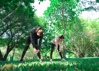 Asian woman in sportswear stretching and warming up before morning jogging. Sports training, jogging in city park.