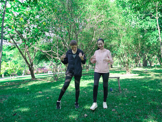 Asian woman in sportswear stretching and warming up before morning jogging. Sports training, jogging in city park.