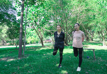 Asian woman in sportswear stretching and warming up before morning jogging. Sports training, jogging in city park.