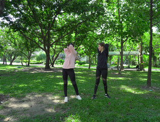 Asian woman in sportswear stretching and warming up before morning jogging. Sports training, jogging in city park.