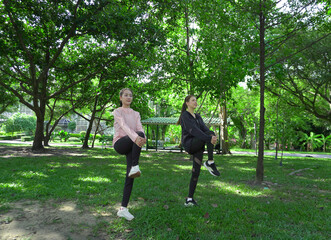 Asian woman in sportswear stretching and warming up before morning jogging. Sports training, jogging in city park.