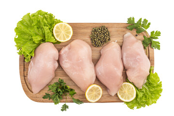 raw chicken breasts on a cutting board with lemons parsley and parsley