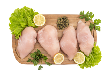 raw chicken breasts on a cutting board with lemons parsley and parsley