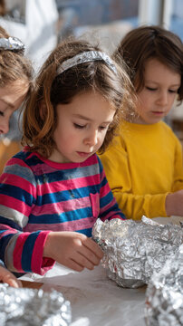 Children crafting with aluminum foil, focused and creative