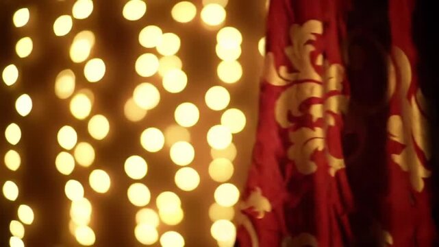 Elegant red curtain with a gold damask pattern hangs beside a wall of warm bokeh lights.