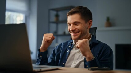Happy man celebrating success while using laptop at home office demonstrating achievement and motivation. - Powered by Adobe