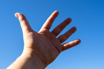 Hand reaching up into sky