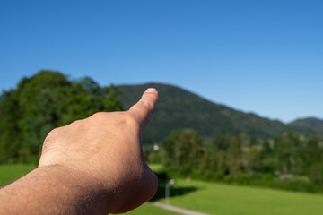 Hand pointing towards mountain in landscape 