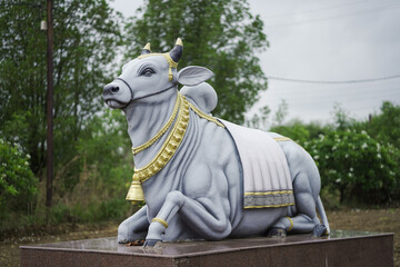 Nandi bull statue outdoors,Religious bull statue IndiaTraditional Nandi with jewelry,Holy bull sculpture in nature,Hindu bull sculpture view stock photo.




