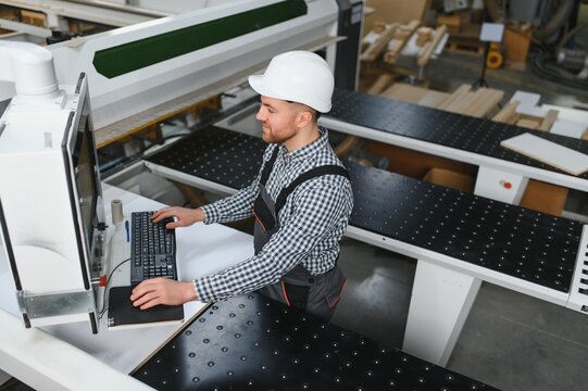 Skilled worker operating cnc machine in furniture factory - Powered by Adobe