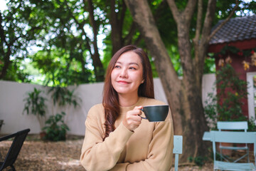 Portrait image of a woman holding and drinking coffee in the outdoors cafe