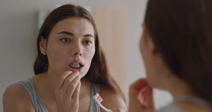 Young woman looking at her red bleeding gums	