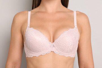 Woman wearing beautiful pink bra on light grey background, closeup