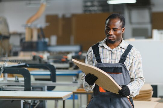 Carpenter examining wood panel in furniture factory
