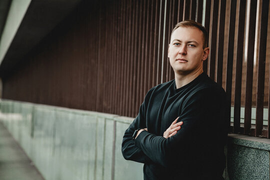 Man standing with arms crossed near modern wall