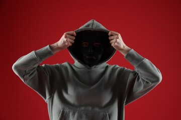 Anonymity. Woman wearing mask on red background