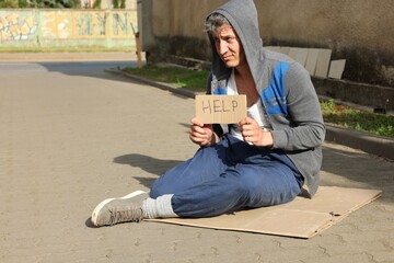 Homeless man with sign Help on carton outdoors, space for text