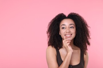 Beautiful Brazilian woman with healthy skin on pink background. Space for text