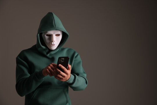 Anonymity. Masked man with smartphone on grey background, space for text - Powered by Adobe