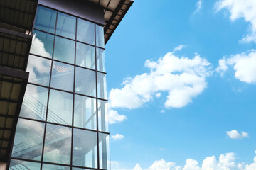 Modern glass office building with reflection on sky and white clouds background.