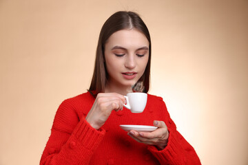 Woman drinking coffee from cup on beige gradient background
