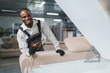 African american Furniture maker assembling sofa in upholstery workshop
