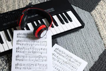 MIDI keyboard, music sheets and headphones on carpet, above view