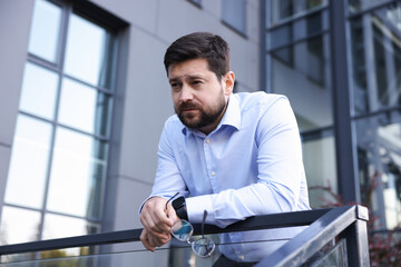Fototapeta premium Tired businessman with glasses outside office building