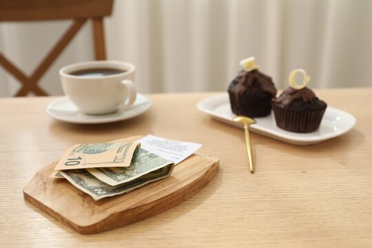 Tips, receipt and order on wooden table in restaurant, closeup. Gratuity for work