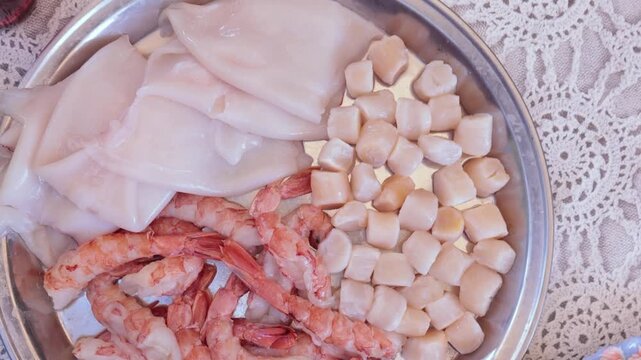Scallops without shells, shrimp and squid on a plate, cooking seafood