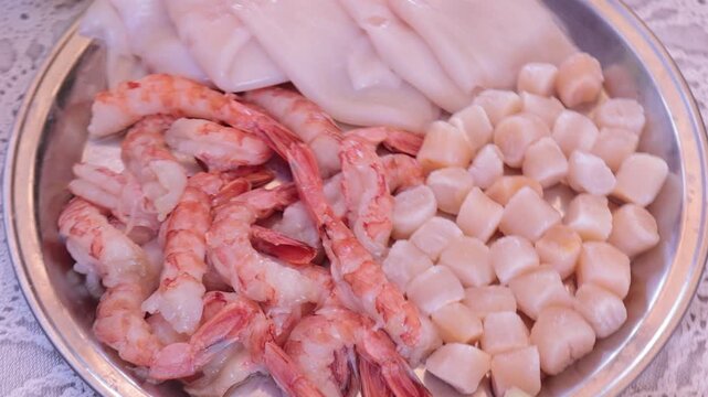 Scallops without shells, shrimp and squid on a plate, cooking seafood