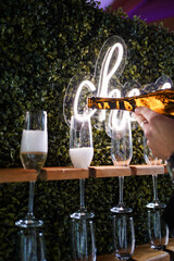 Champagne is poured into glasses on a stand.