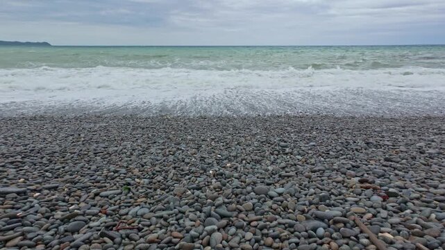 Small waves on a tropical pebble beach on an overcast day. 