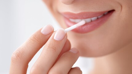 Close-up of person applying lip balm or gloss to lips with fingers for moisturization.