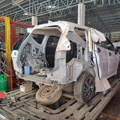 Car undergoing structural repairs in a car repair shop, showing the mechanisms, disassembly, and tools involved in the car repair process.