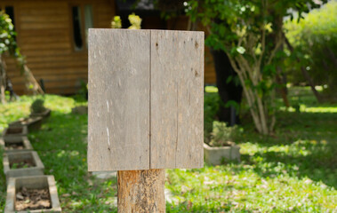 A blank weathered wooden sign on wooden pole seting in green park