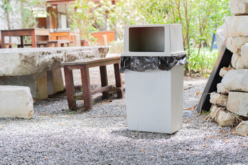 Park seating, wooden tables and benches picnic with a grey trash can settin on a small stone ground floor.
