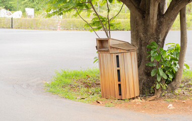 Public park in spring with wooden trash can setting under big trees