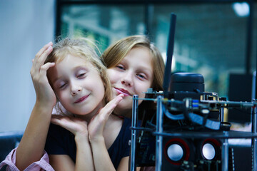 Happy schoolgirls in technology class collaborating on a robotic project with curiosity and...