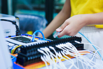 Close-up of child’s hand inserting LAN cable into network device, showing young learners engaging...