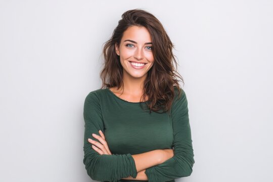 Happy young woman with curly brown hair wearing casual green sweater smiling at camera.