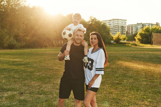 Family of father, mother and young son on the field with soccer ball - Powered by Adobe
