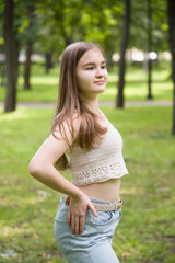 young brunette smiling woman in hand made top posing in sunny park near tree on summer 