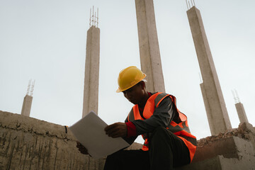 Frustrated male construction engineer wearing a hard hat looks stressed and overwhelmed at a job...