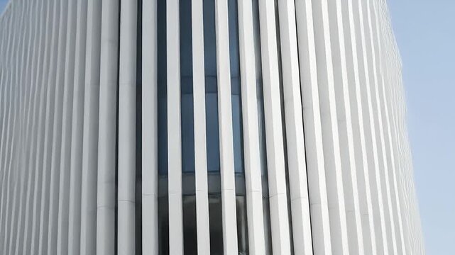 Modern building facade with vertical white louvers and dark windows