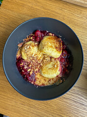 A delicious bowl of berry cobbler topped with golden biscuits and sprinkled with crunchy granola, inviting and visually appealing.