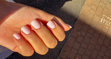 A close-up of a woman's hand with neatly manicured light pink nails, showcasing elegance and style.